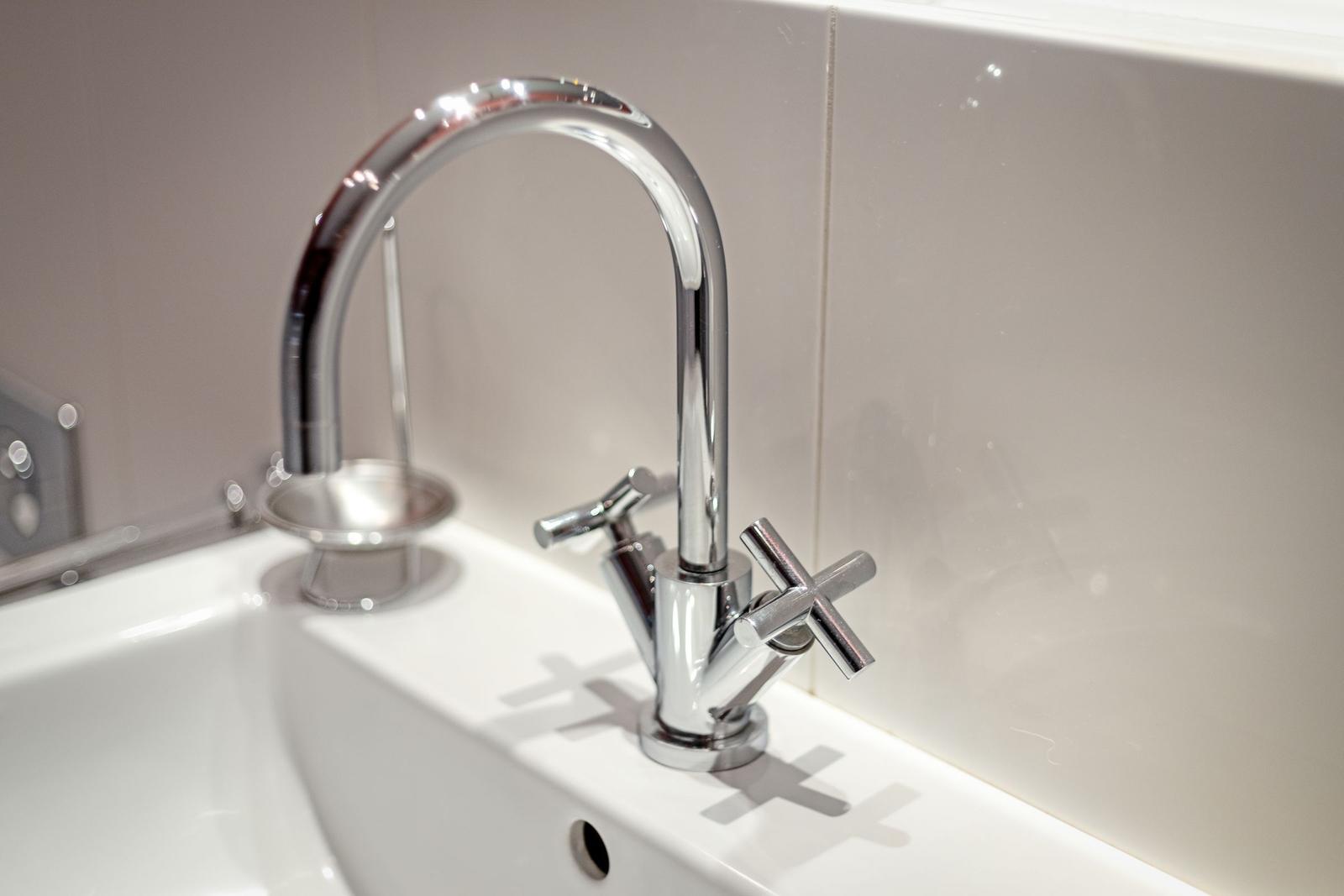 Moderne Waschbecken mit chromfarbenem Wasserhahn und zwei Handgriffen.