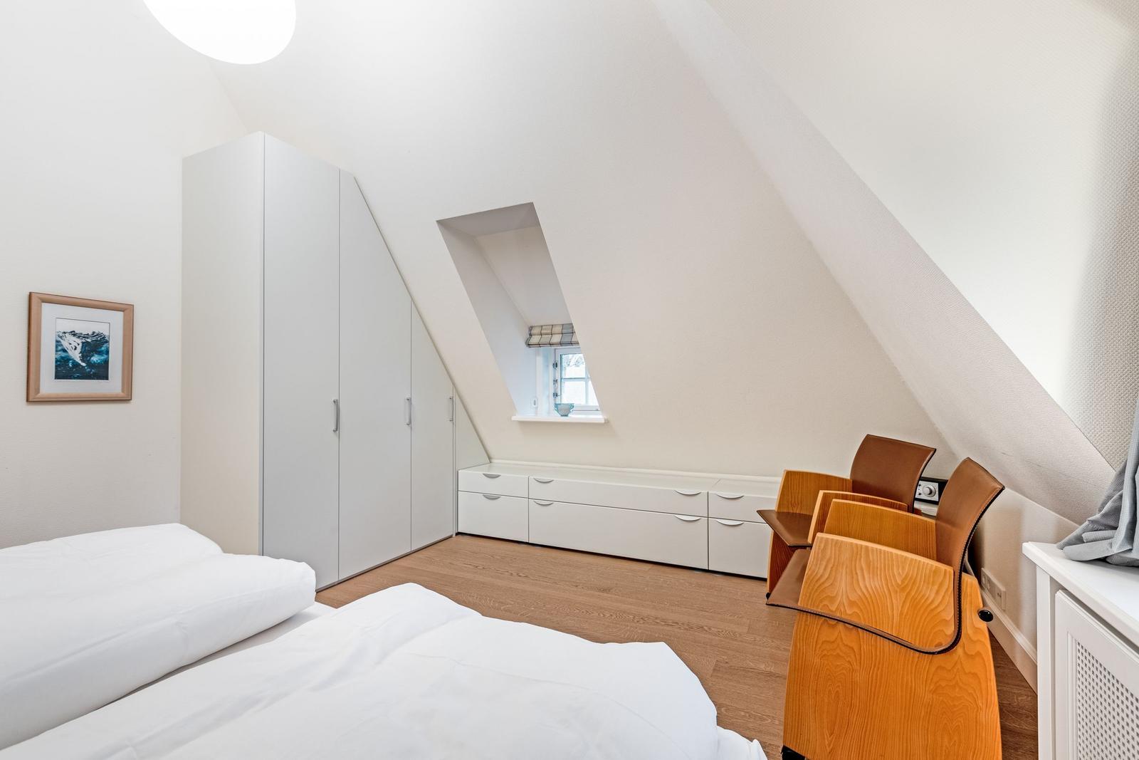 Schlafzimmer mit Dachschräge, Bett, Kleiderschrank und Fenster