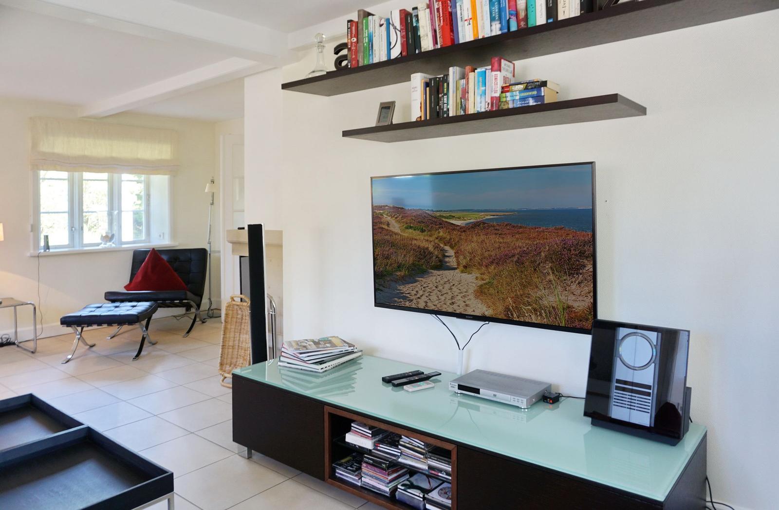 Wohnzimmer mit TV, Bücherregalen und Sitzgelegenheit.