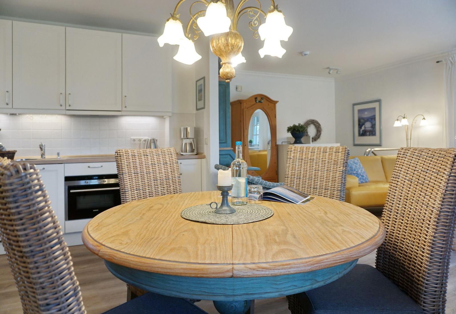 Round table with chairs, kitchen and living area in background.