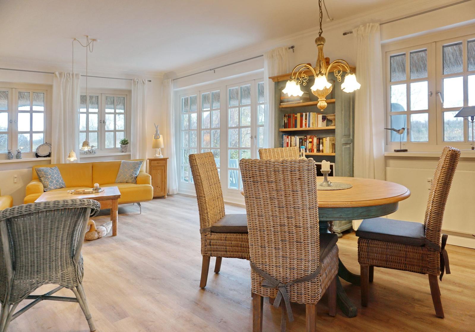 Dining area with round table and chairs, living area with sofa and windows