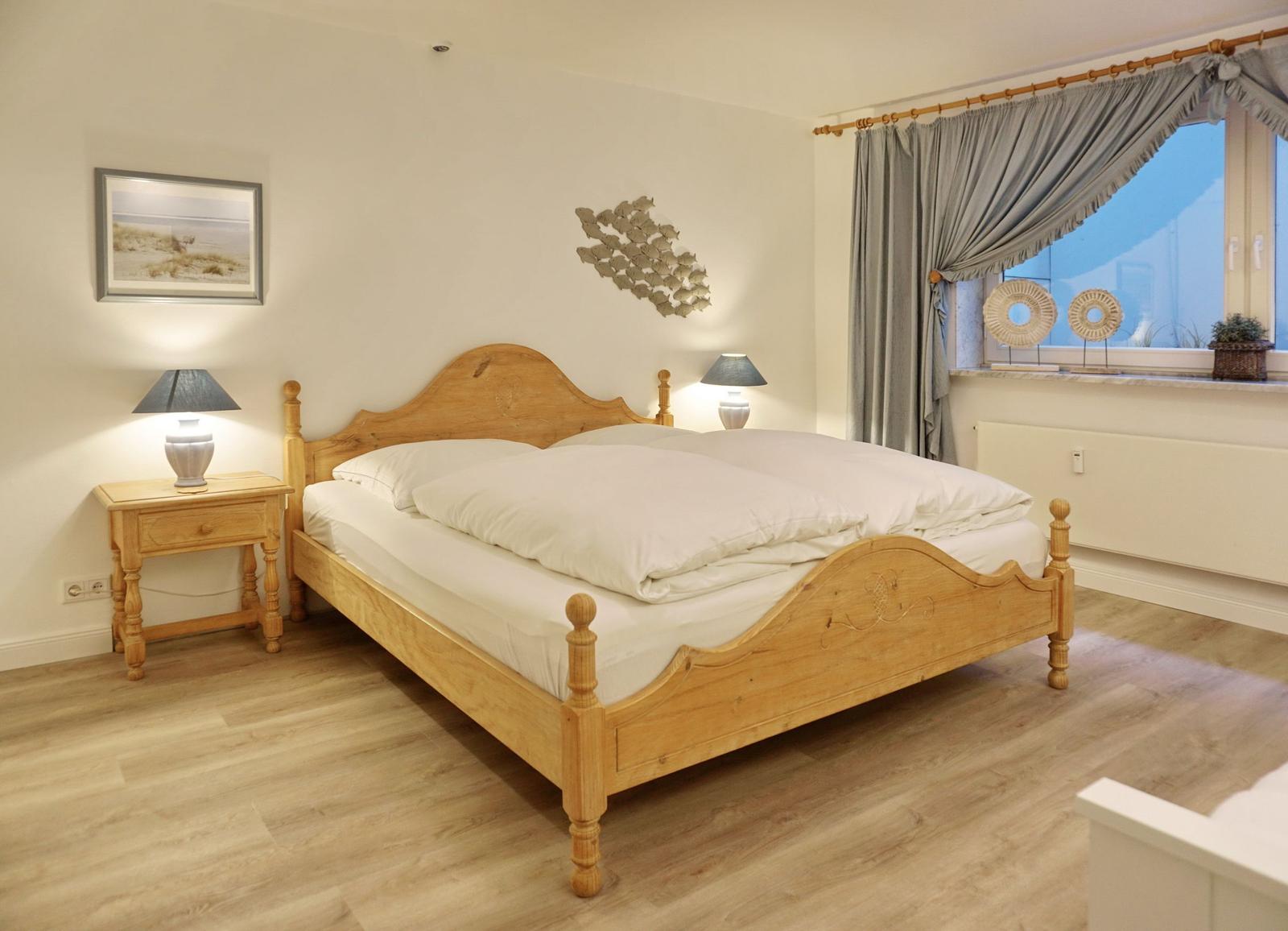 Bedroom with wooden bed, nightstand, and window with curtains.