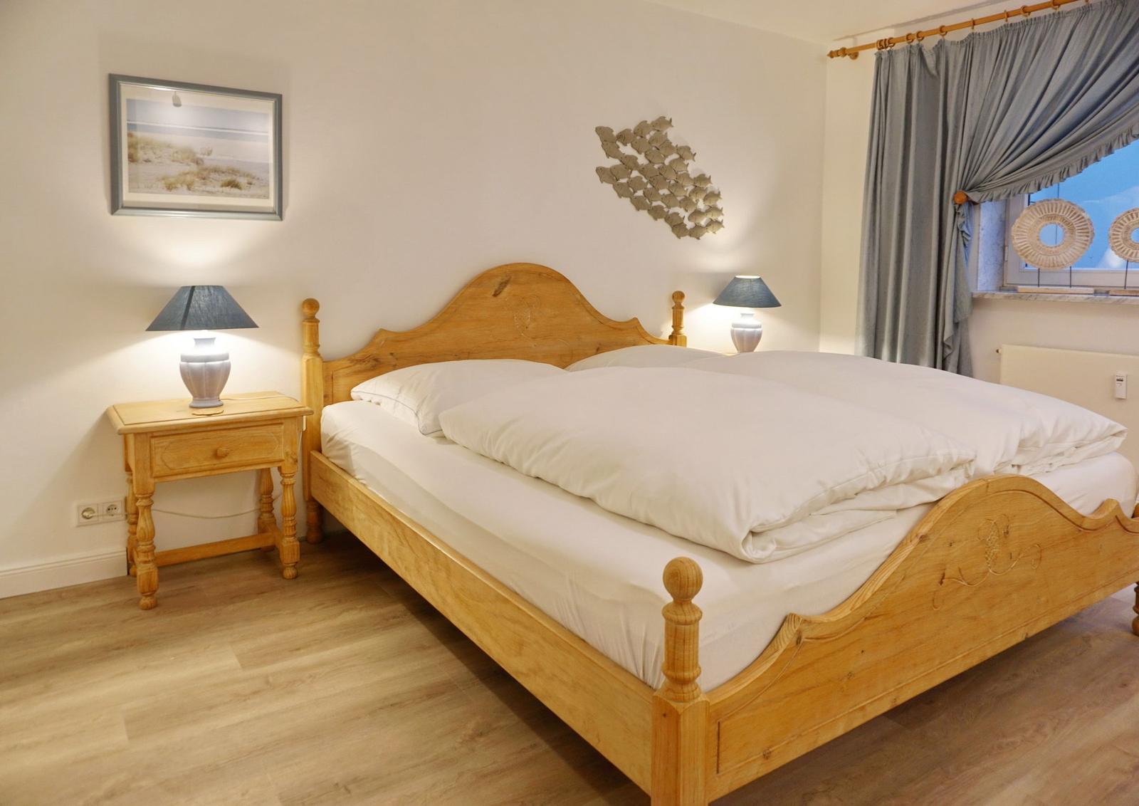 Bedroom with wooden bed, nightstand, and window with curtains.
