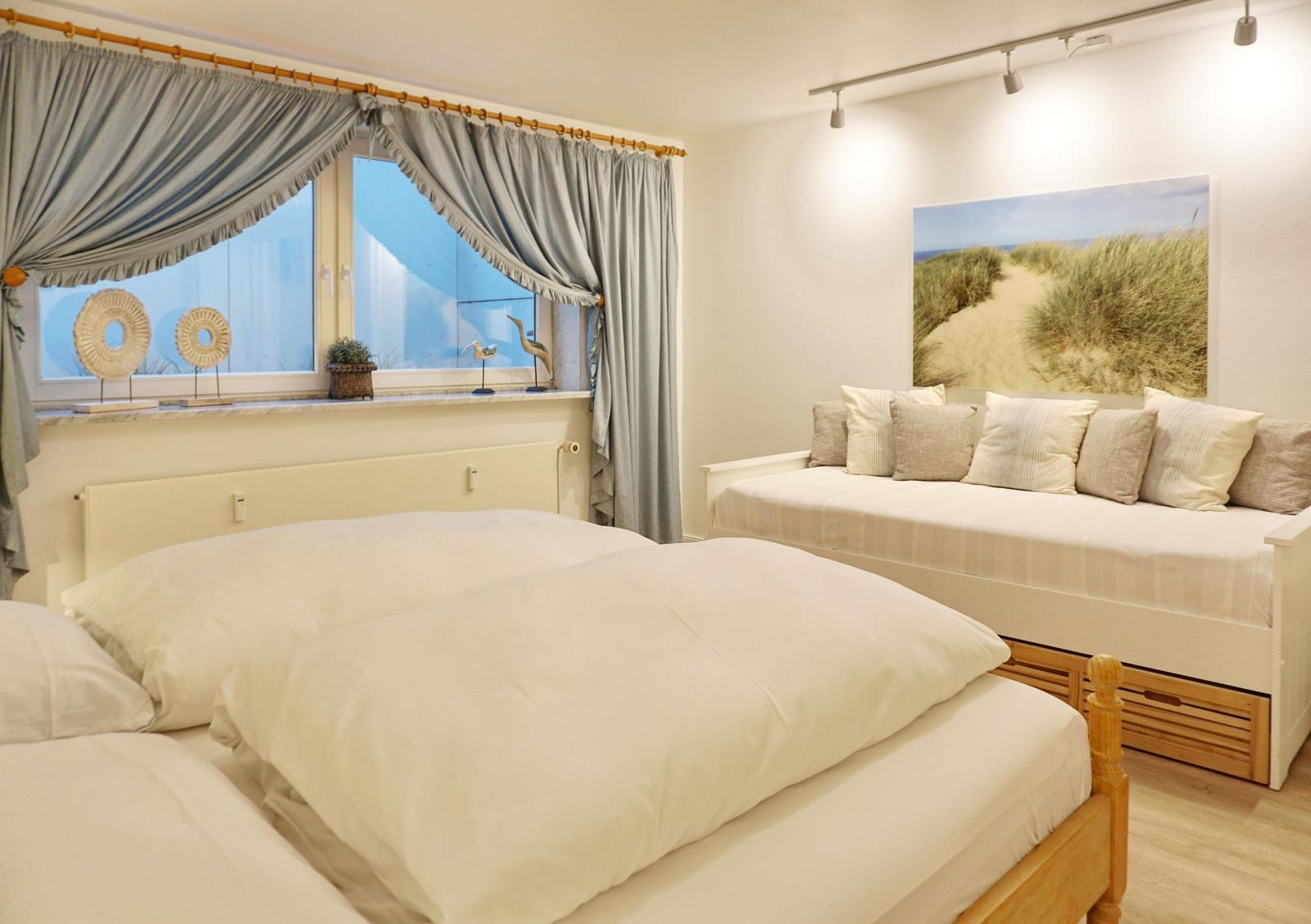 Bedroom with double bed, sofa, and window view.