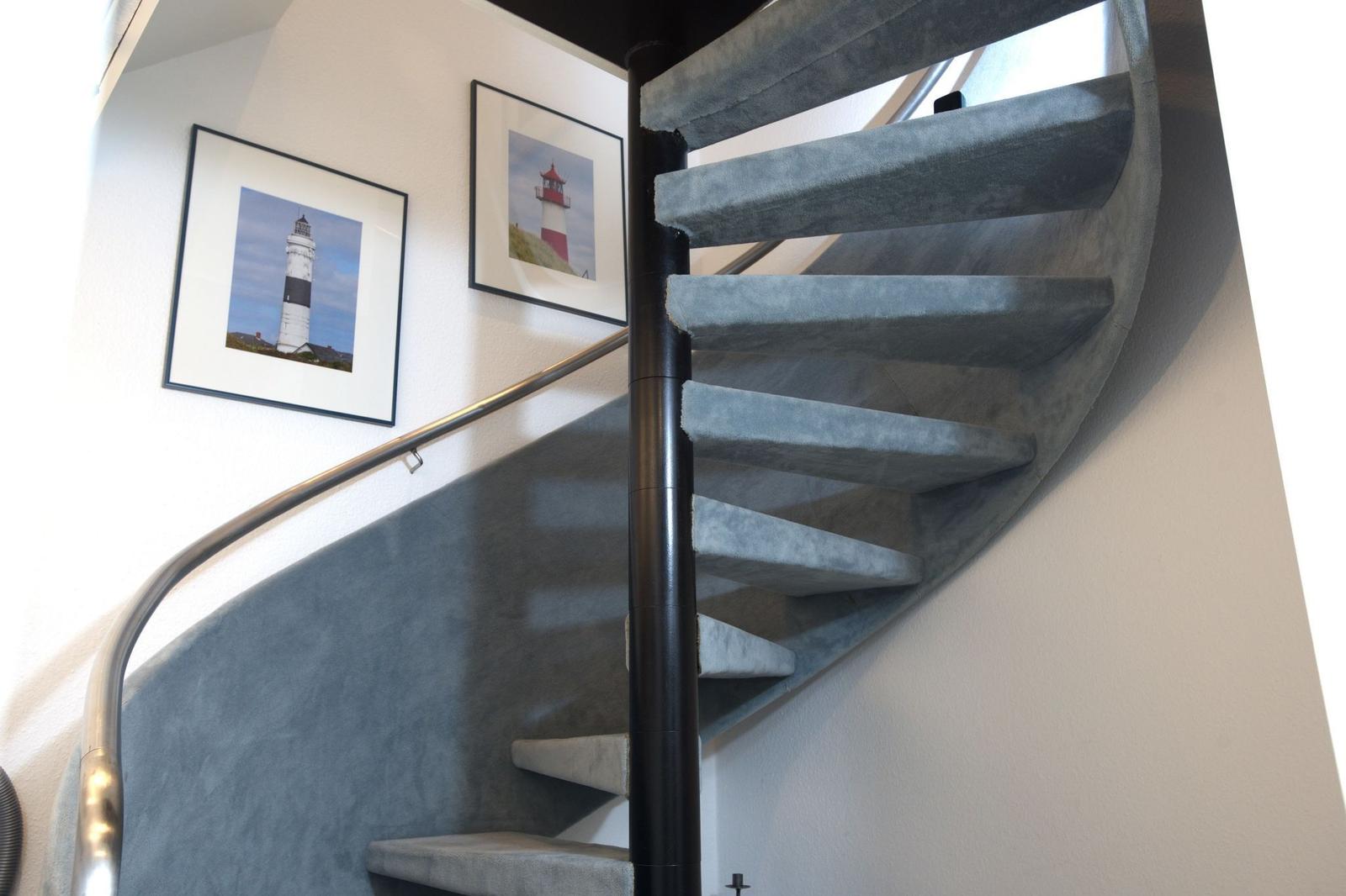 Spiral staircase with blue carpet and two lighthouse pictures on the wall.