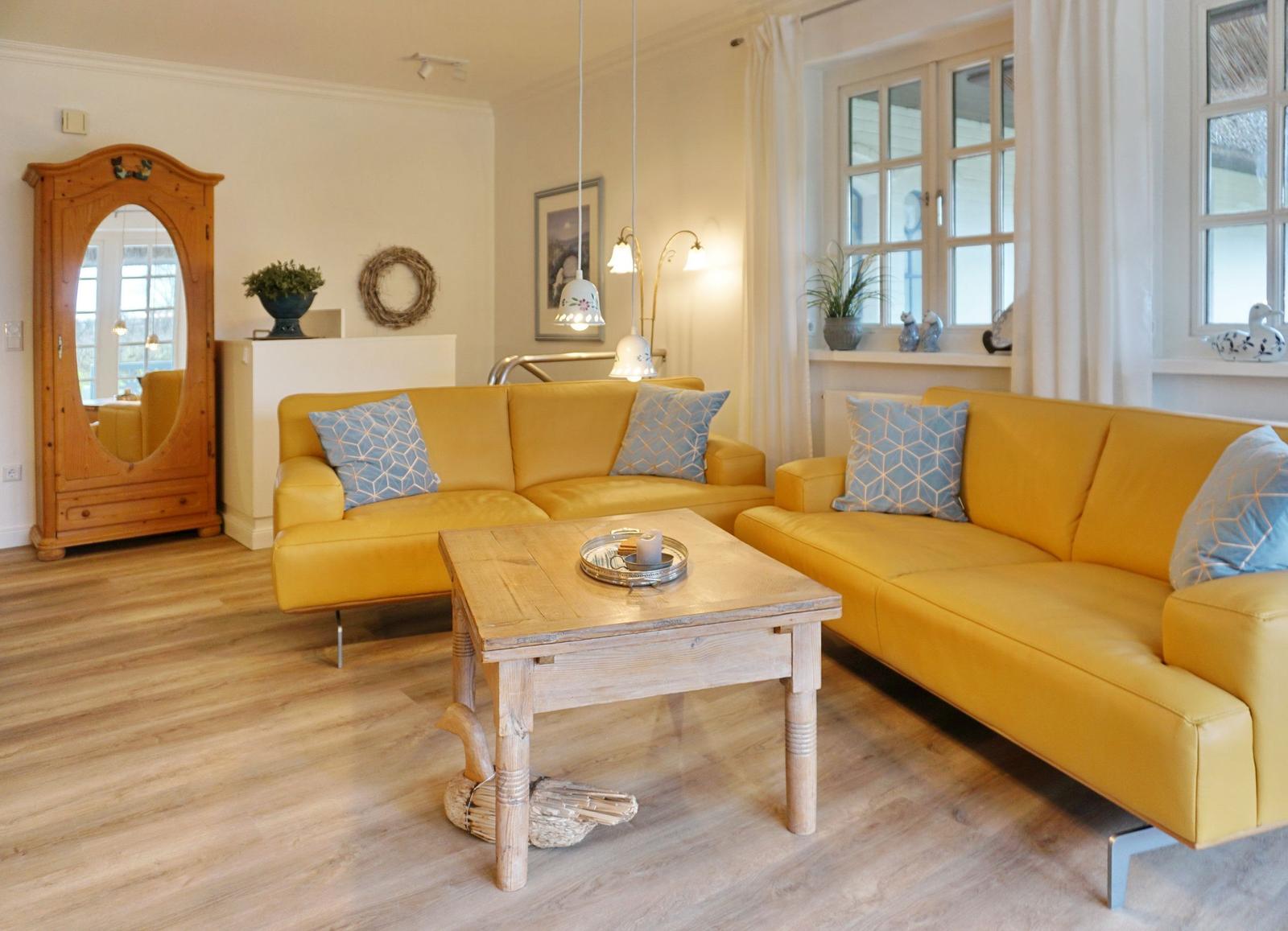 Two yellow sofas with blue cushions around a wooden table.
