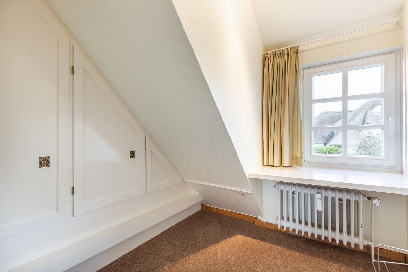 Dachgeschosszimmer mit Fenster, Vorhang und Heizkörper.