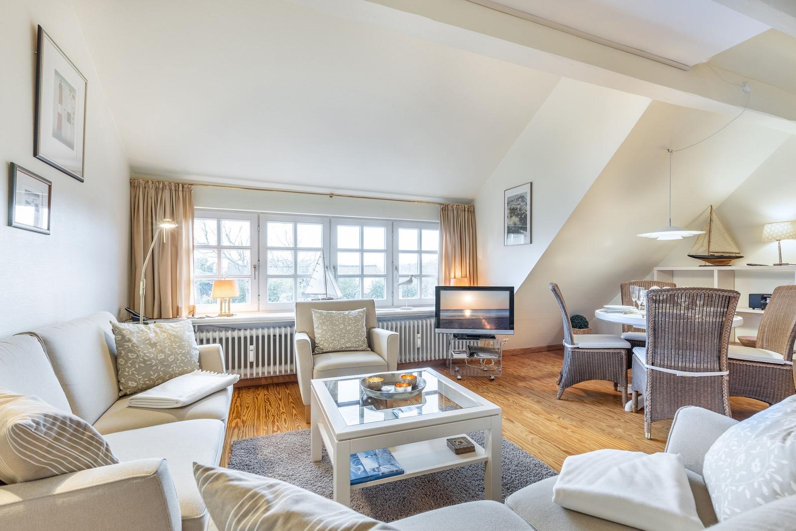 Wohn- und Essbereich mit Sofa, Sessel, Esstisch und Fernseher.