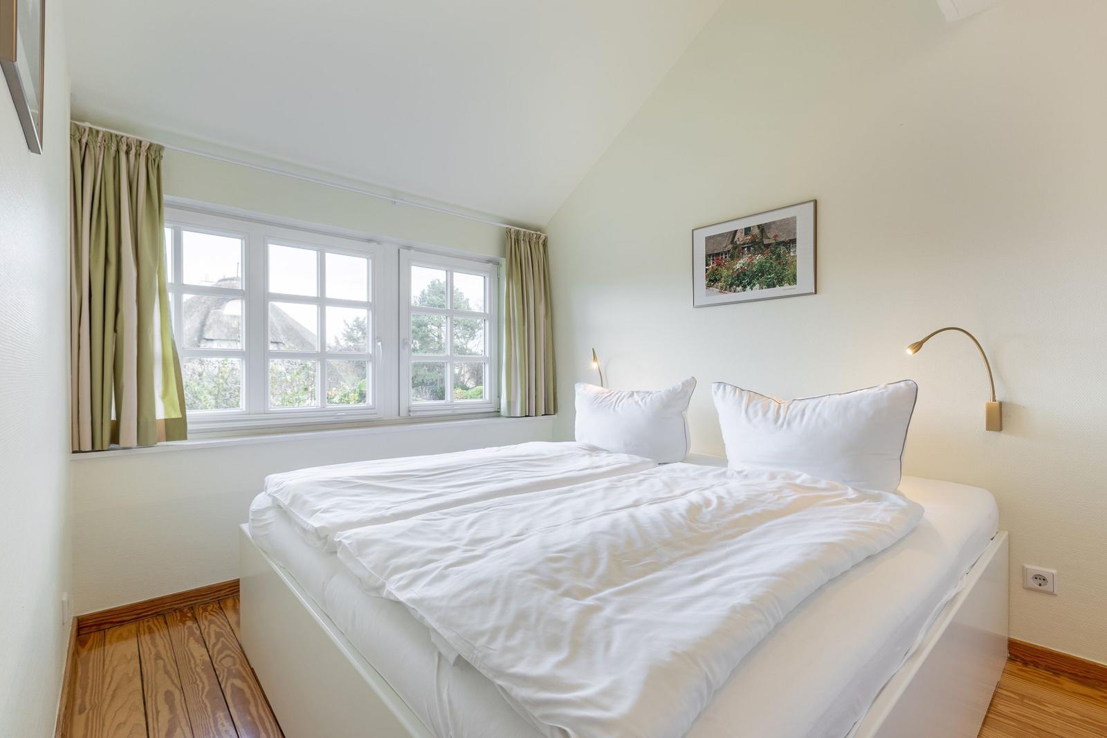 Schlafzimmer mit Doppelbett, Fenster und Wandlampe.