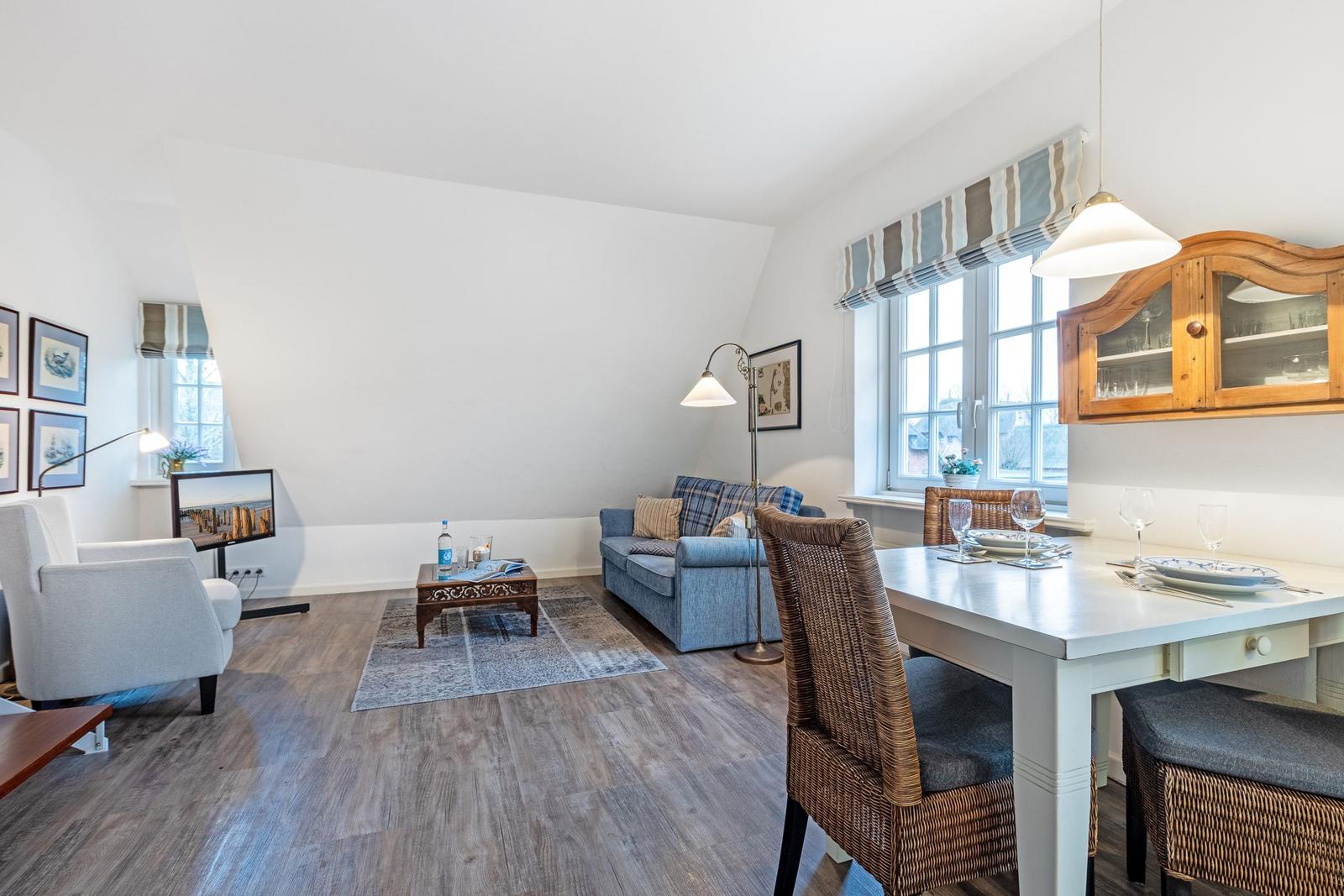 Living and dining area with sofa, TV, and dining table with chairs.