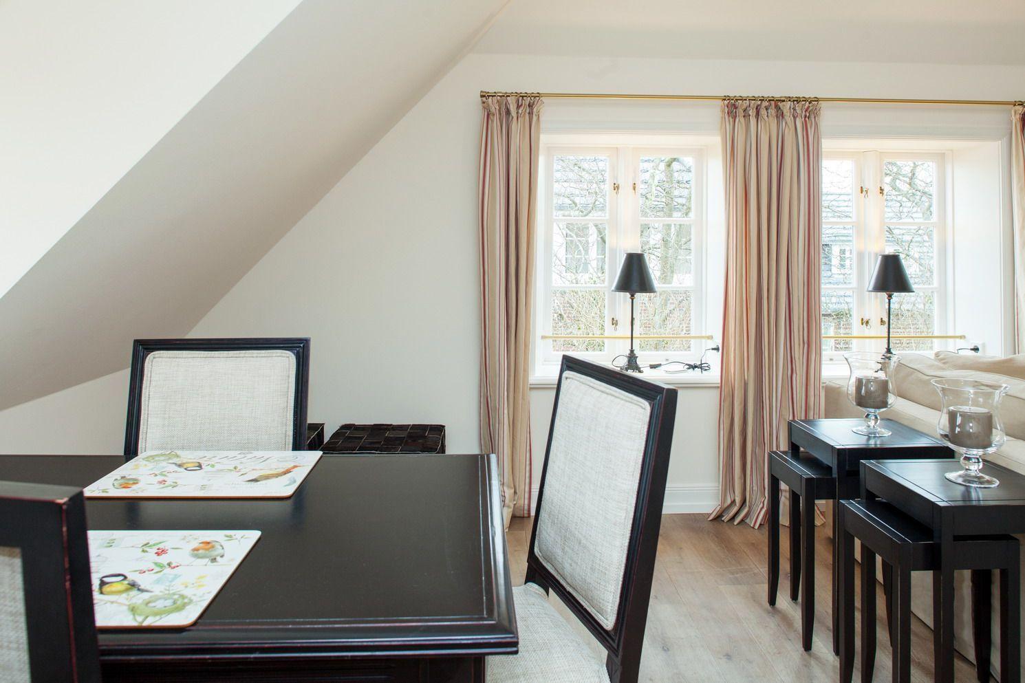 Dining room with table, chairs, and windows with curtains.