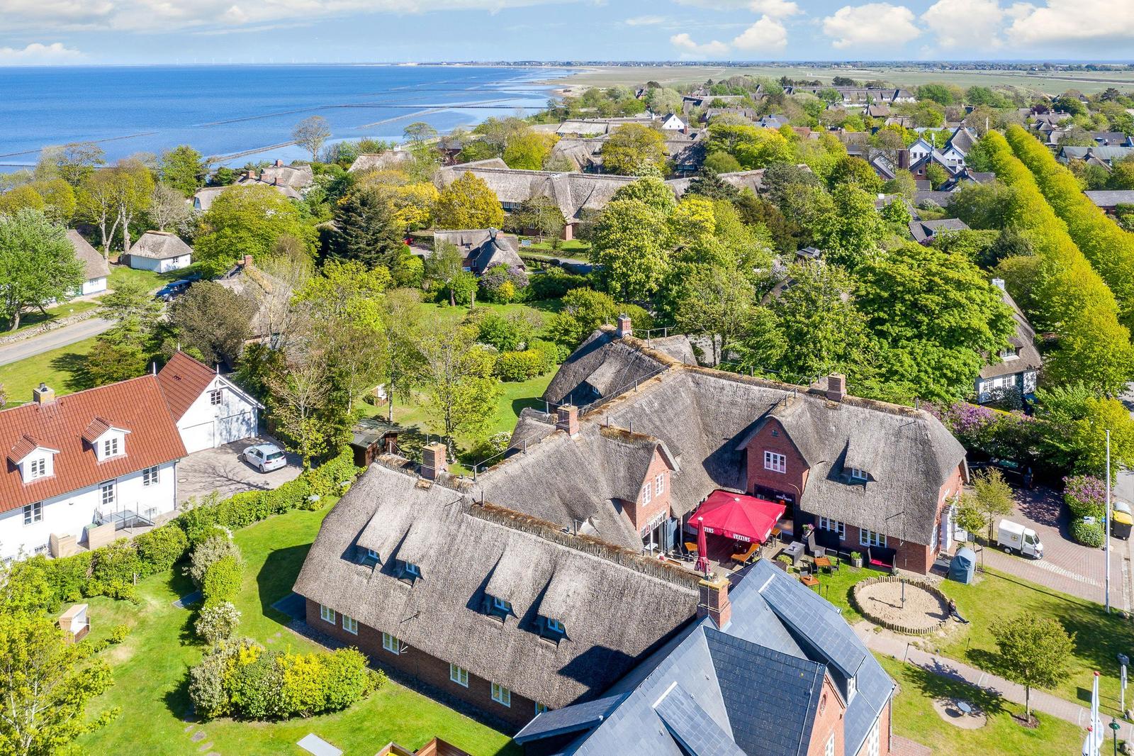 Village with thatched houses and view of the sea.