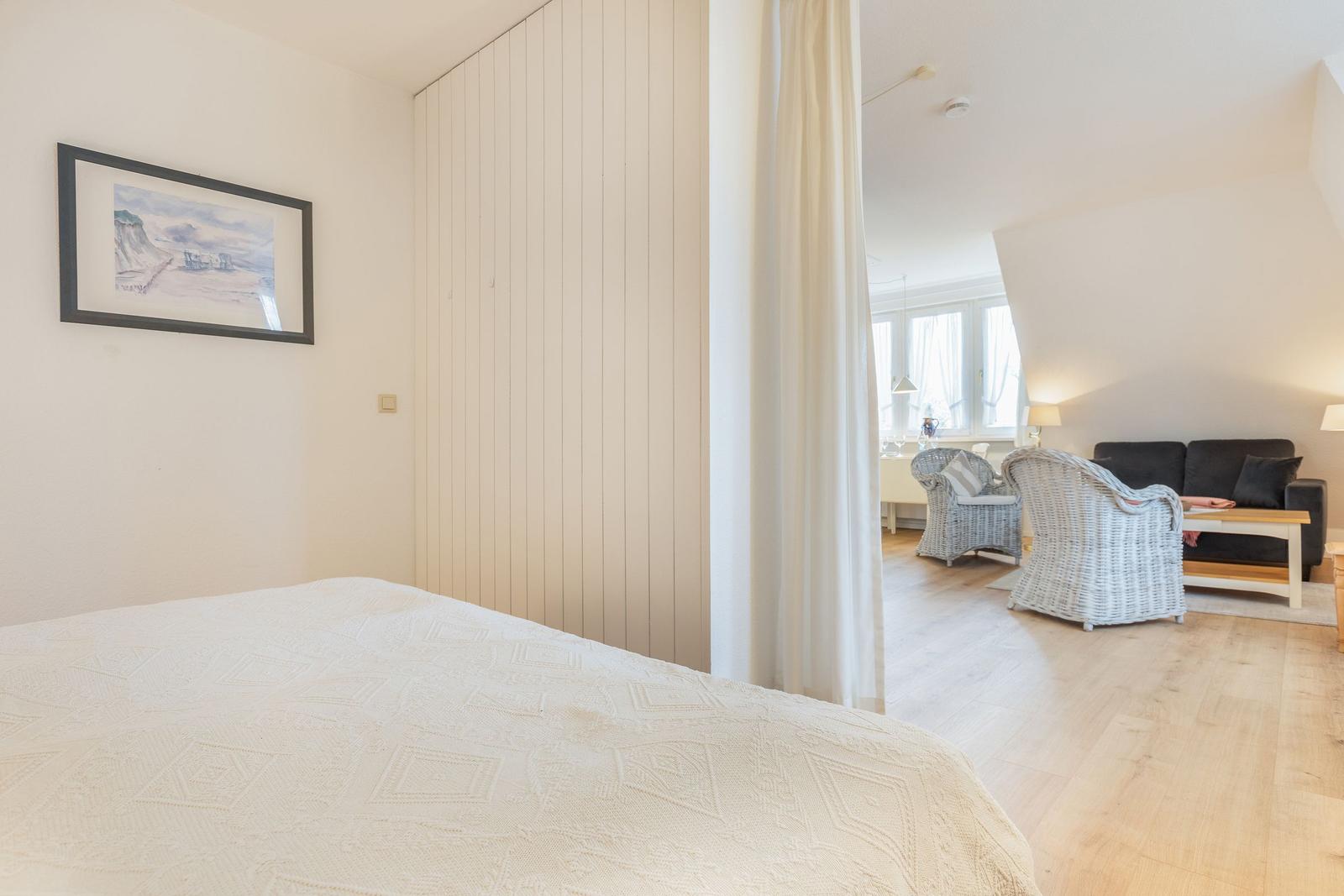 Schlafzimmer mit Blick auf Wohnbereich mit Sofa und Stühlen