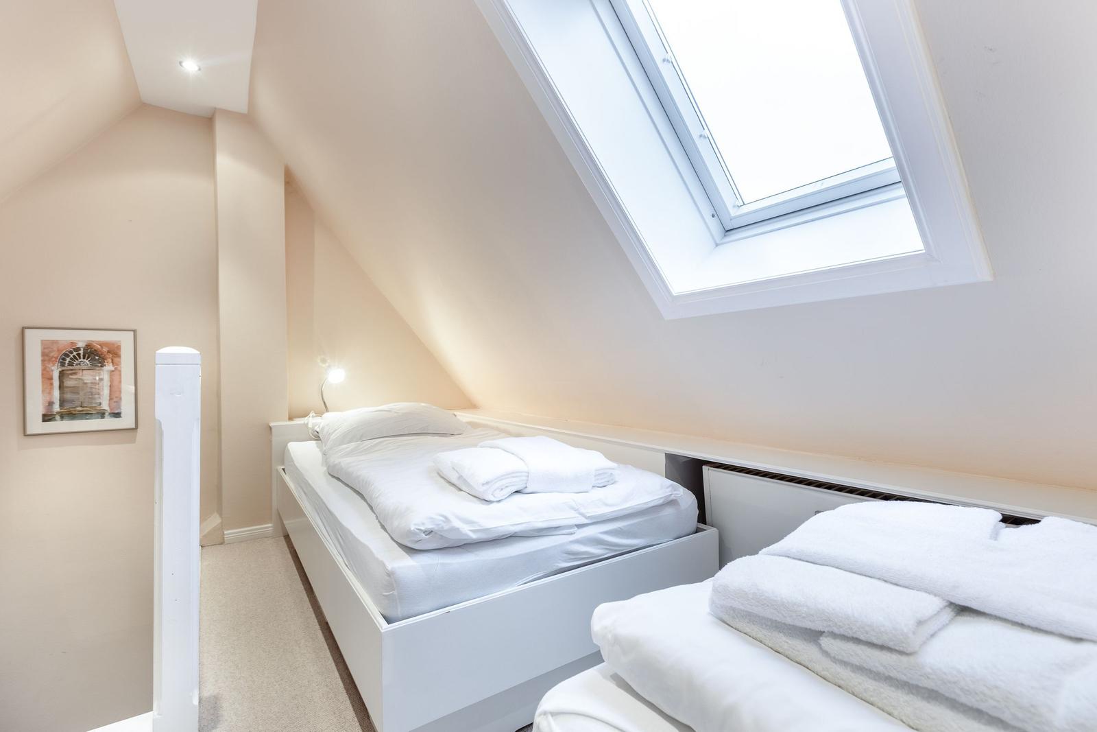 Schlafzimmer mit Dachfenster, Bett und Handtüchern.