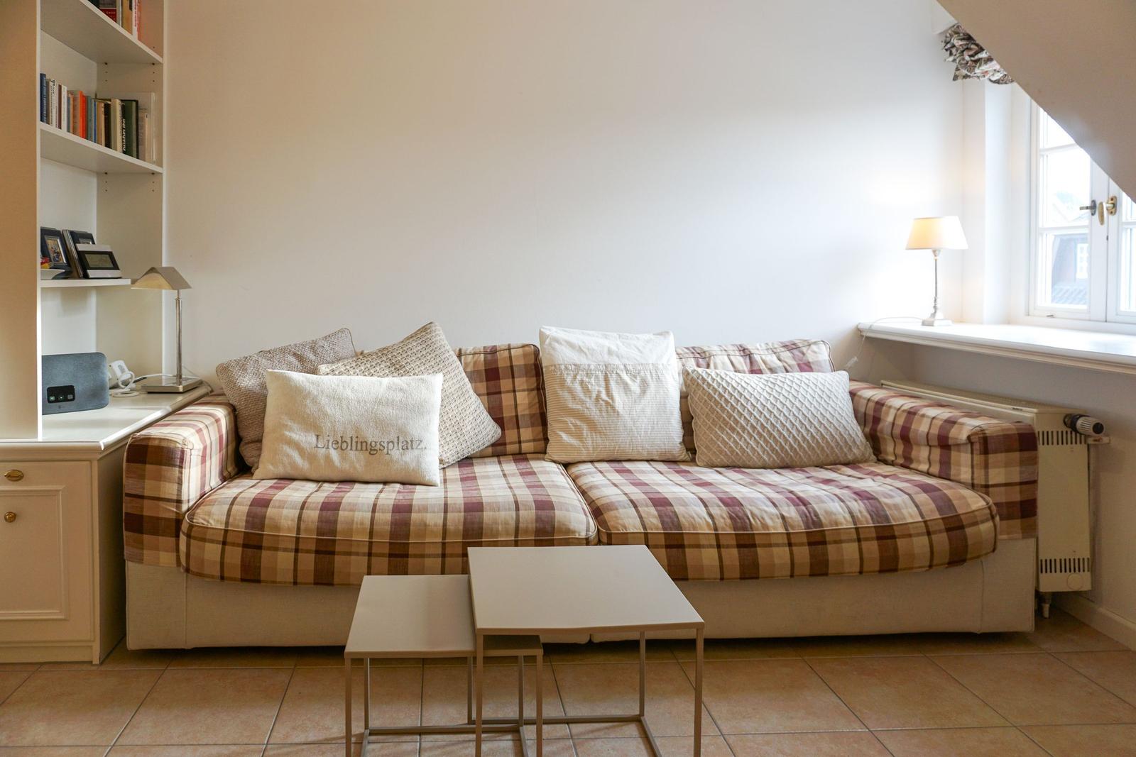 A sofa with checkered upholstery and cushions near a window.
