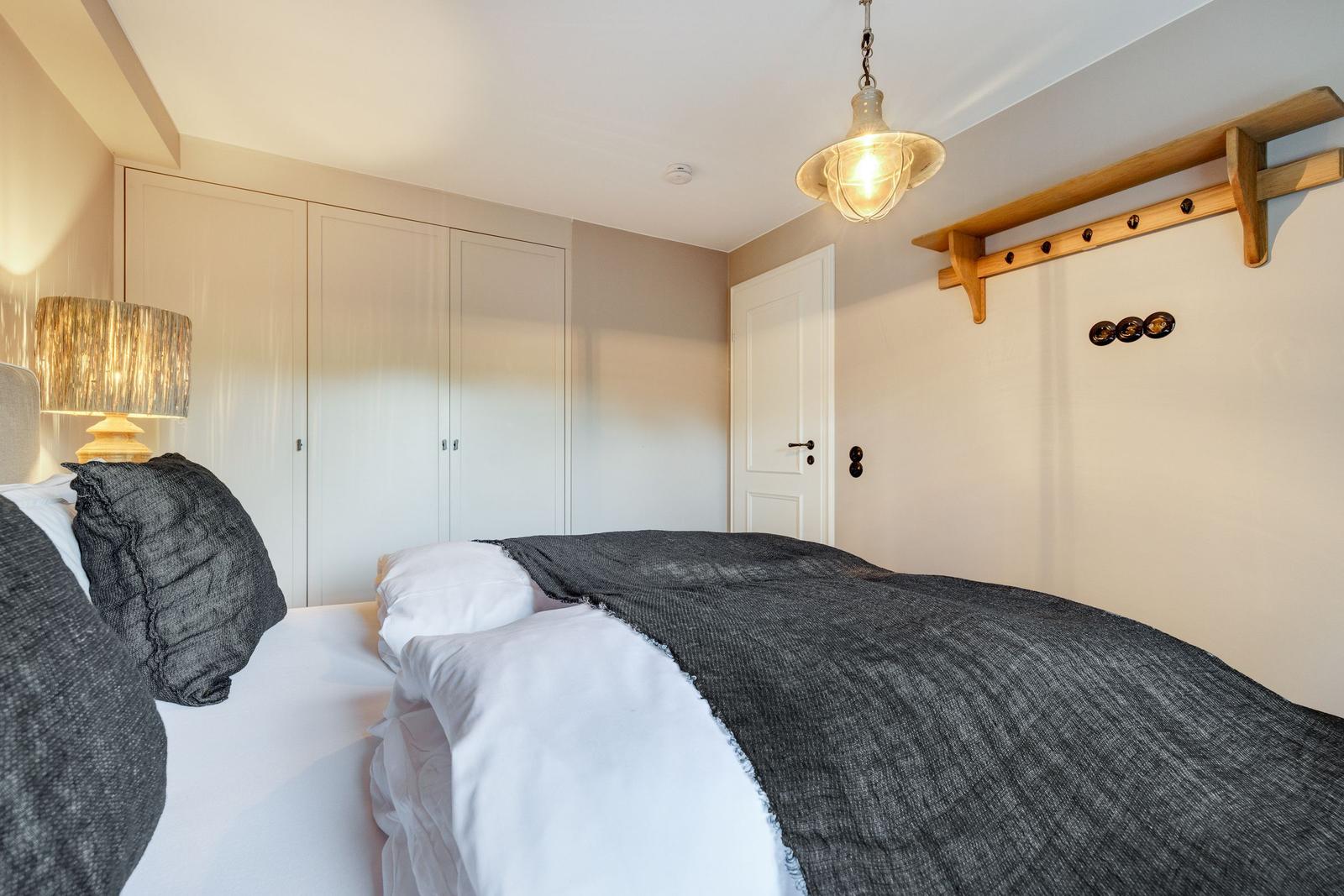 Bedroom with bed, coat rack, and ceiling lamp.