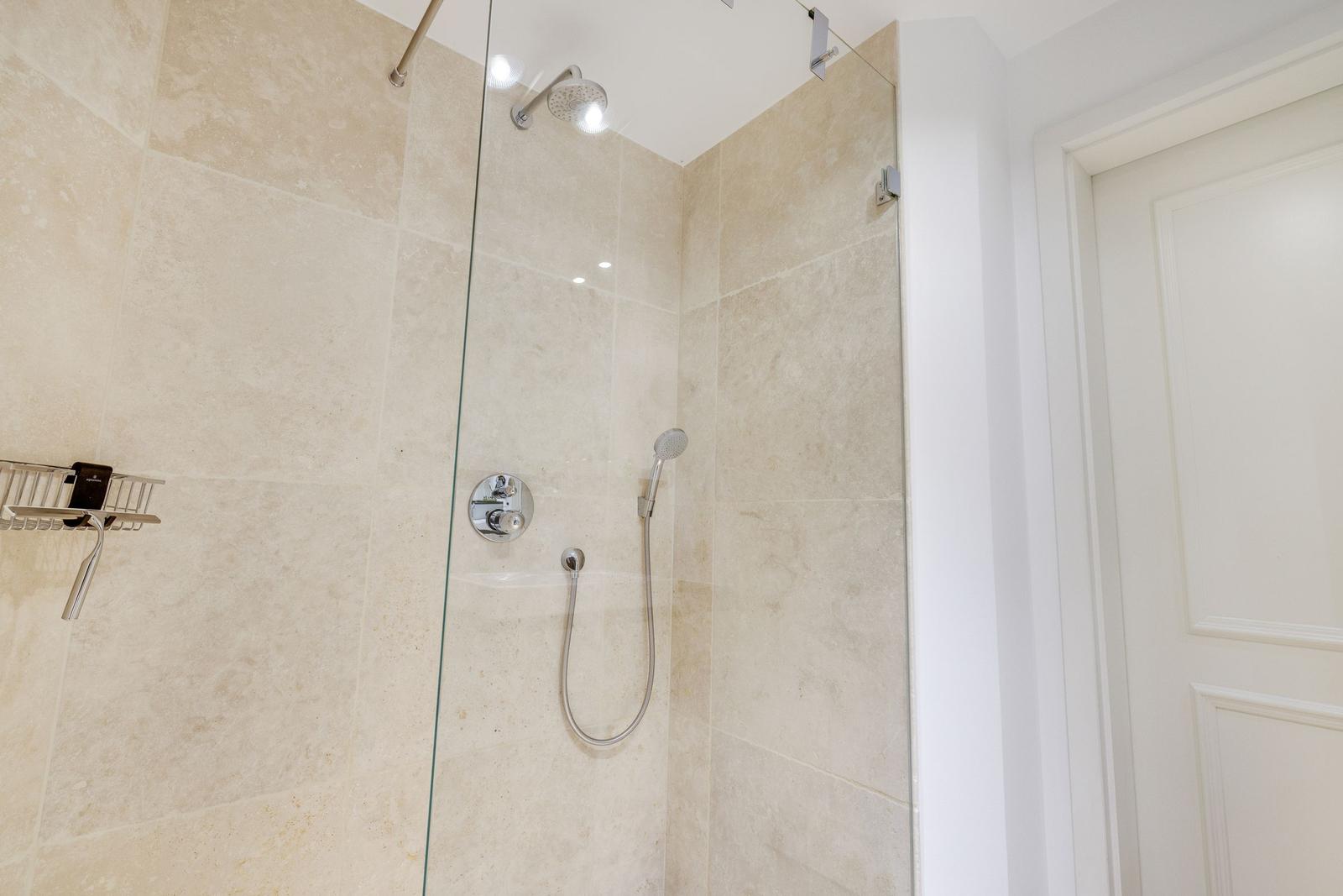Shower with glass enclosure, showerhead, and handheld shower