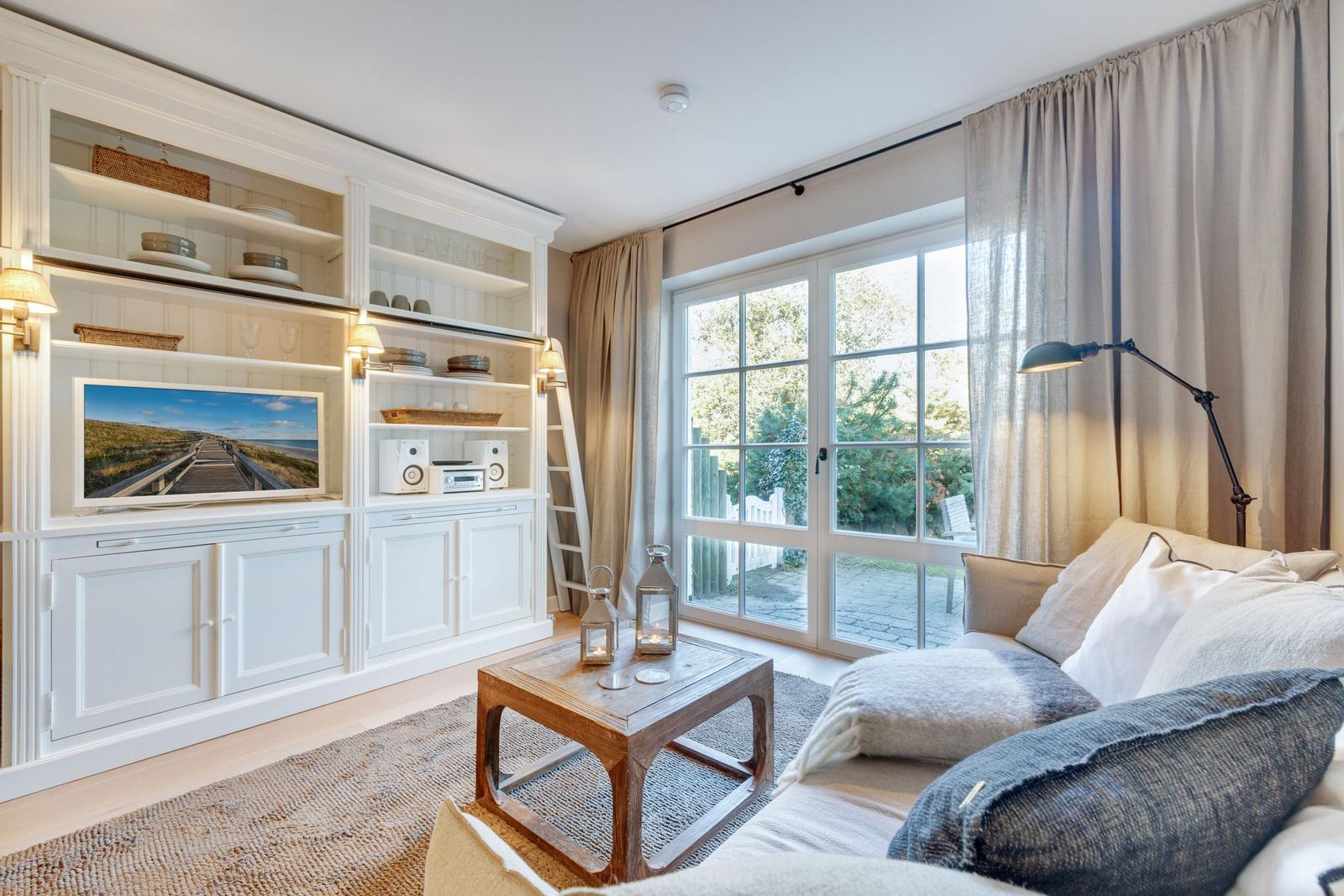 Living room with TV, bookcase, and view of the garden.