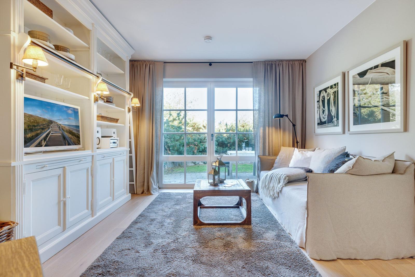 Living room with sofa, TV, and glass door to terrace.