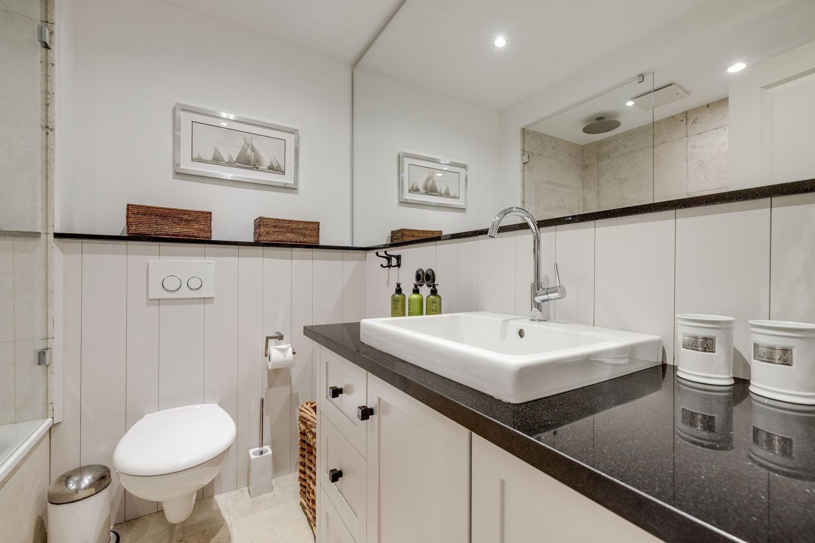 Badezimmer mit Waschbecken, Toilette und Spiegel