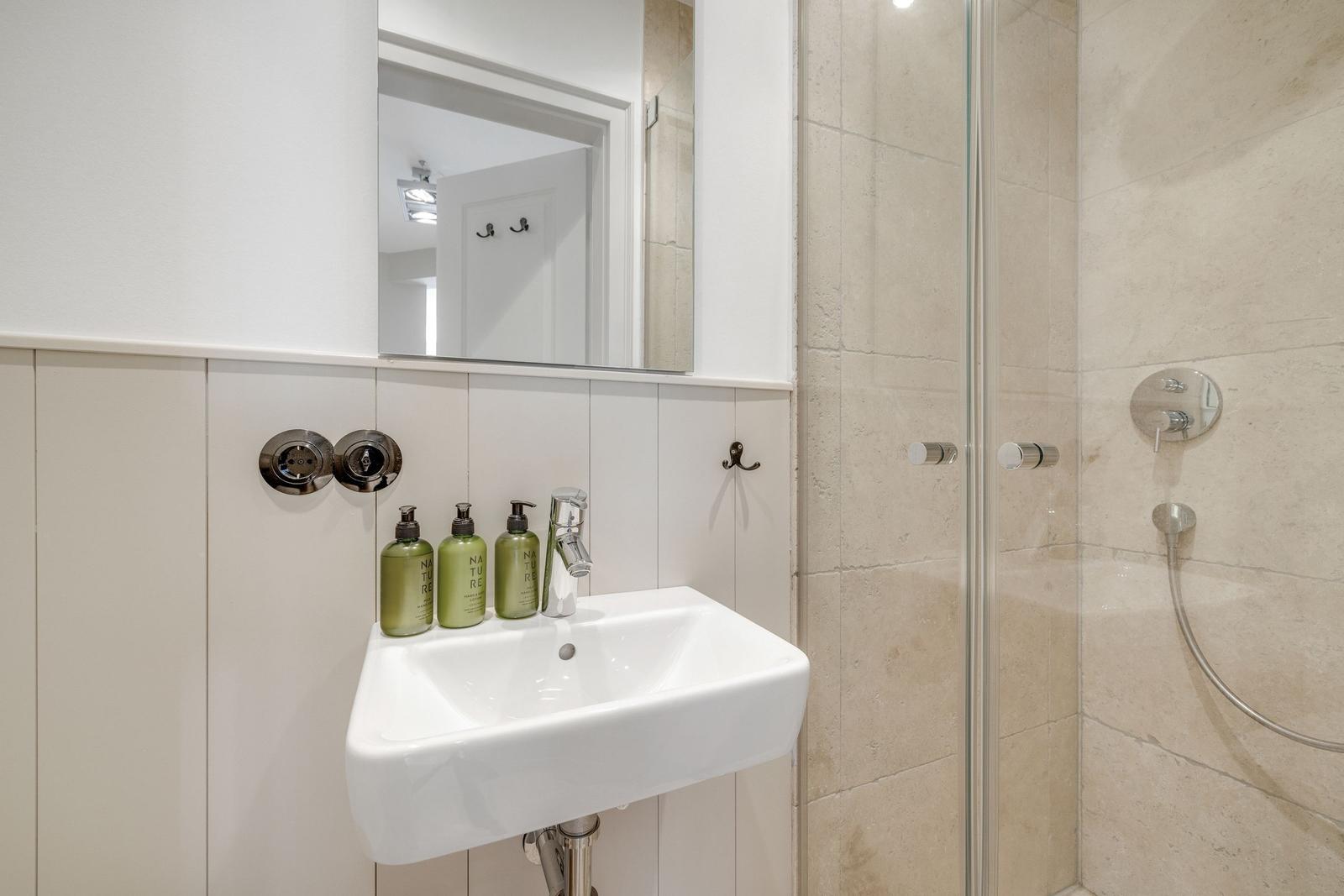 Bad mit Dusche, Waschbecken und Spiegel