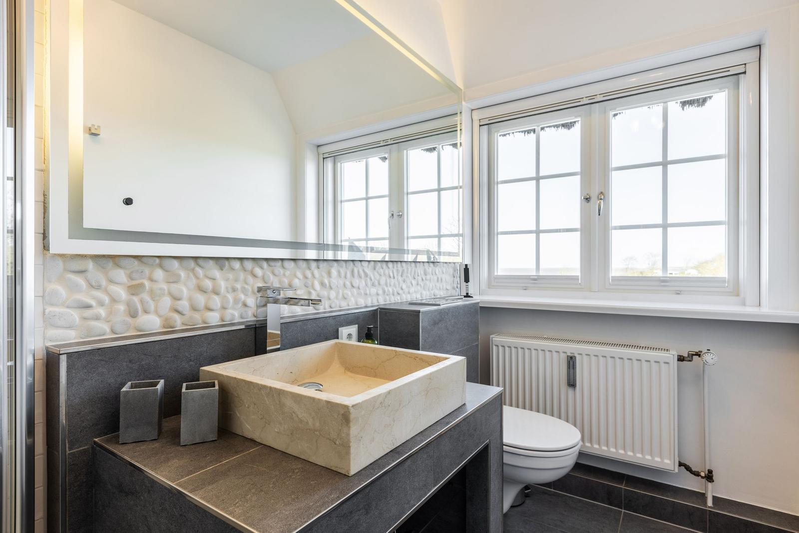 Badezimmer mit Waschtisch, Spiegel und Fenster
