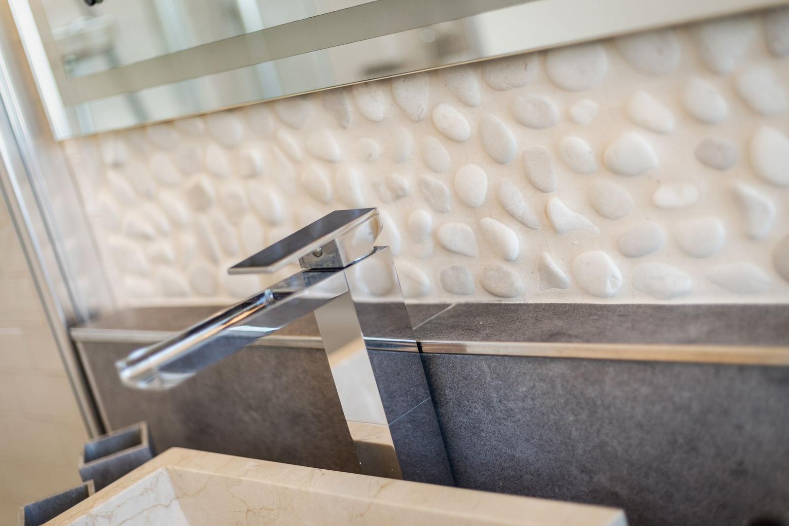 Dusche mit Steinwand und modernem Wasserhahn