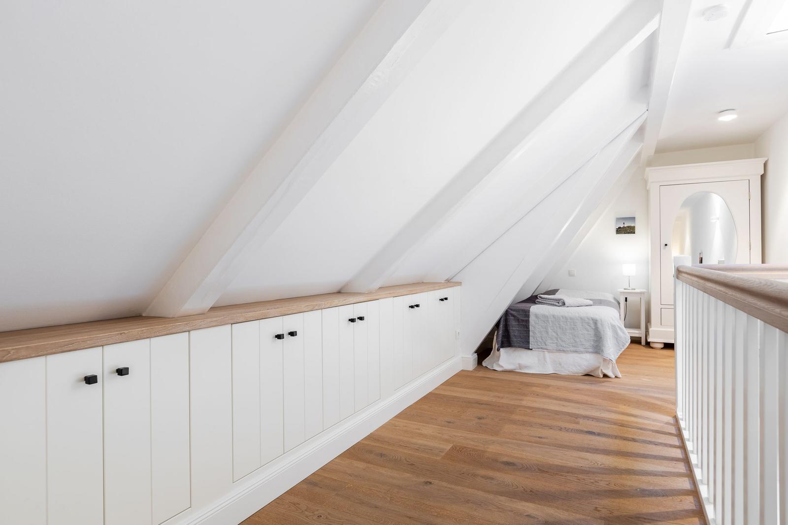 Dachgeschosszimmer mit Bett, Schrank und Holzboden.