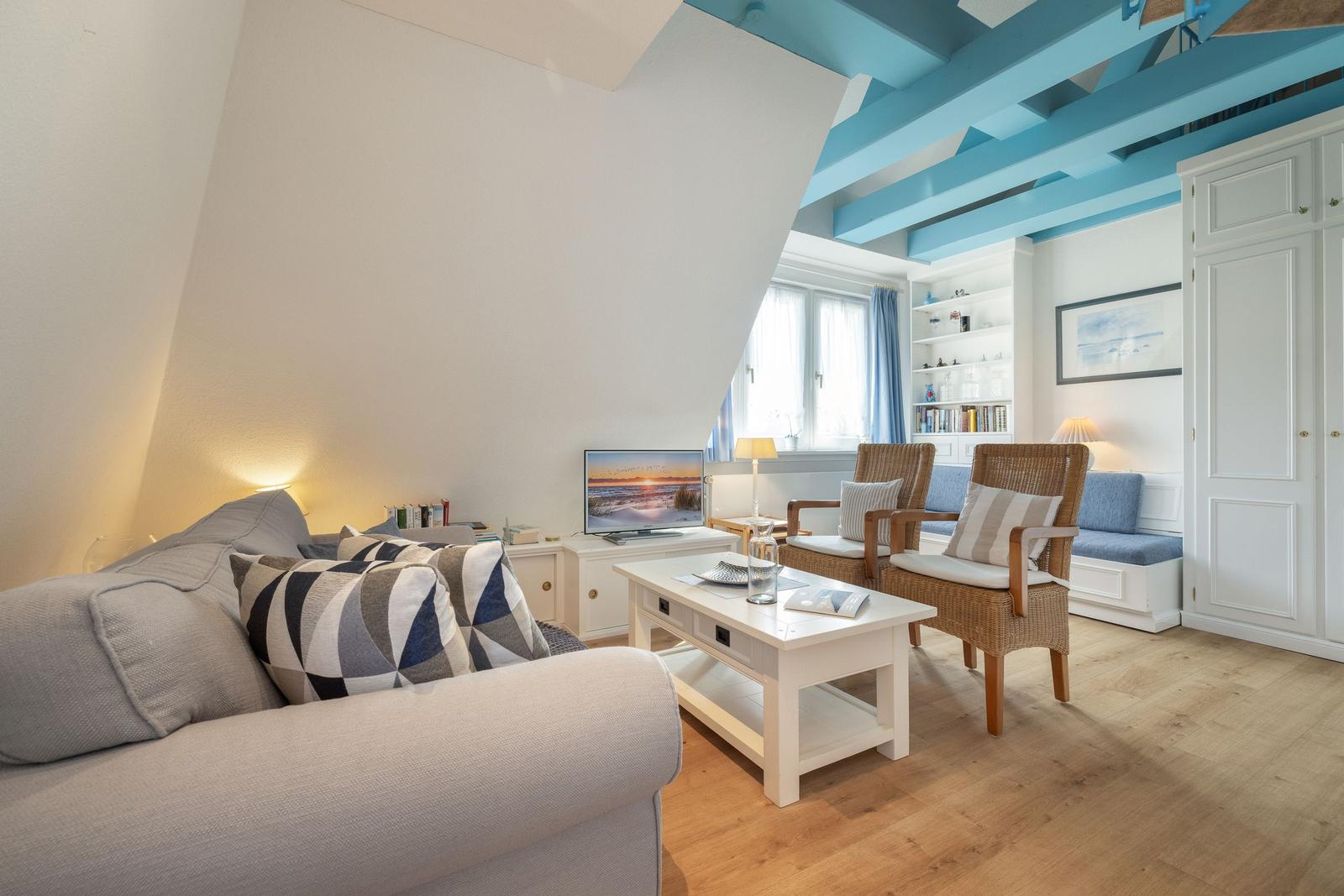 Wohnzimmer mit Sofa, Tisch und Stühlen unter blauen Balken.