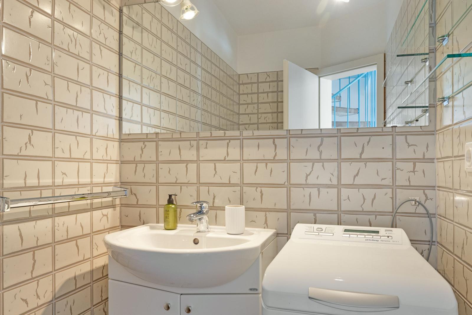 Badezimmer mit Waschmaschine und Spiegelschrank