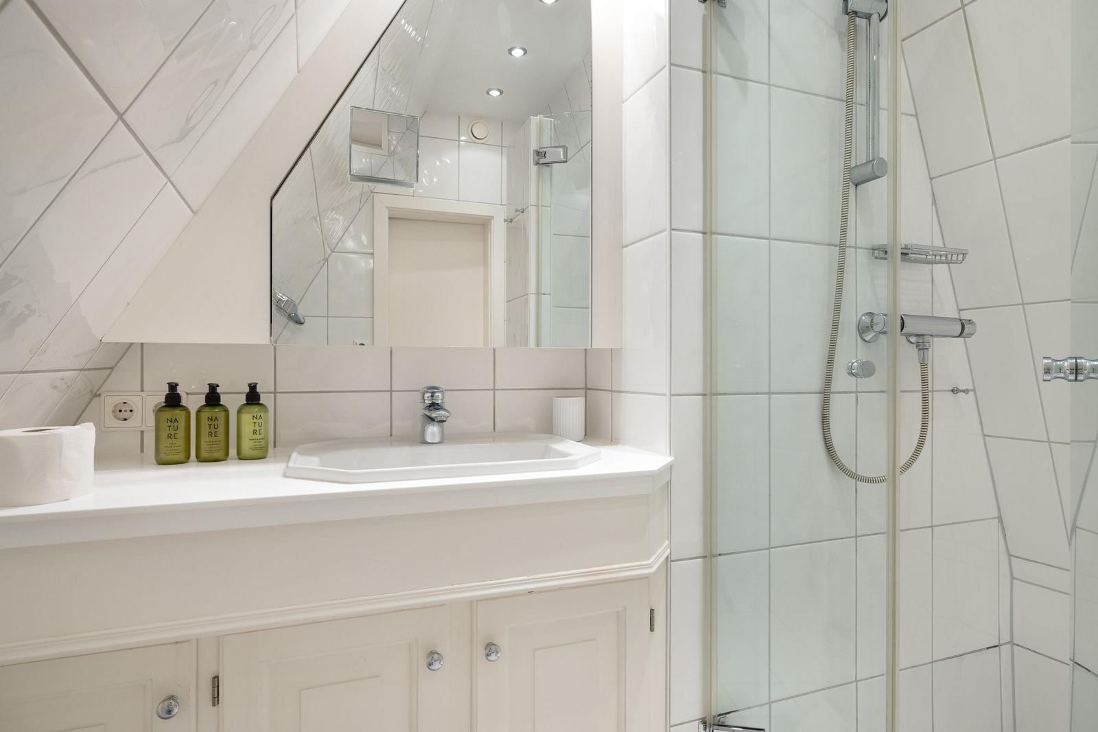Badezimmer mit Dusche, Waschbecken und Spiegel