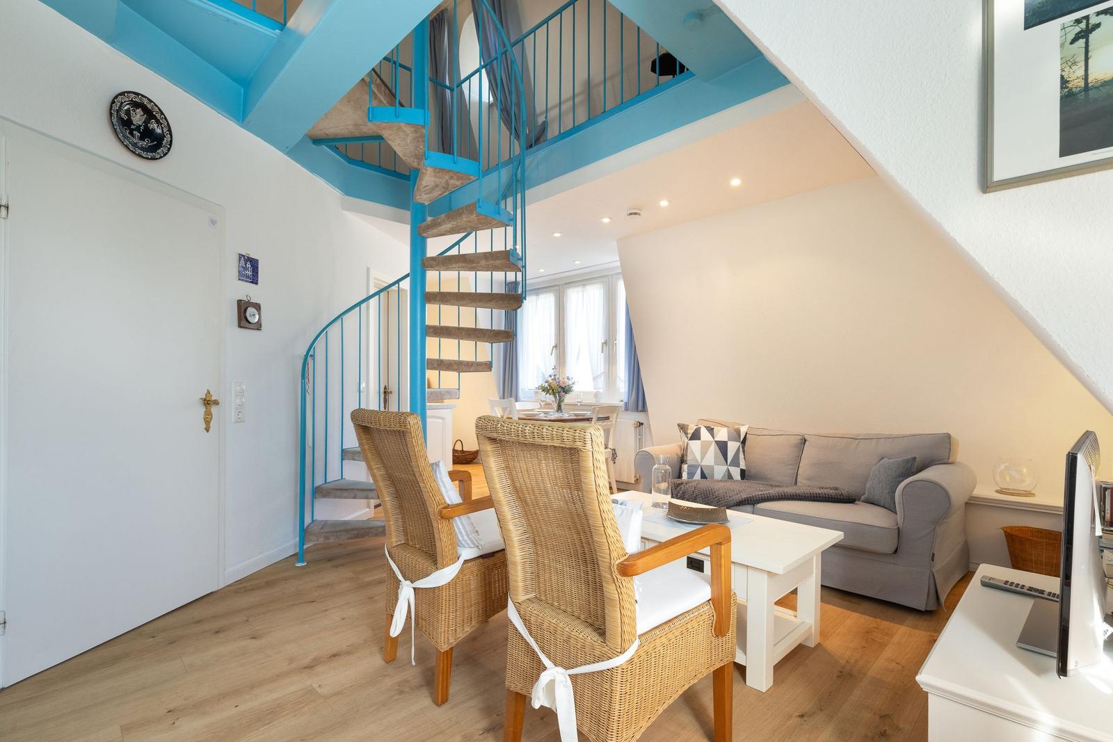 Wohnbereich mit Sofa, Esstisch und blauer Wendeltreppe.