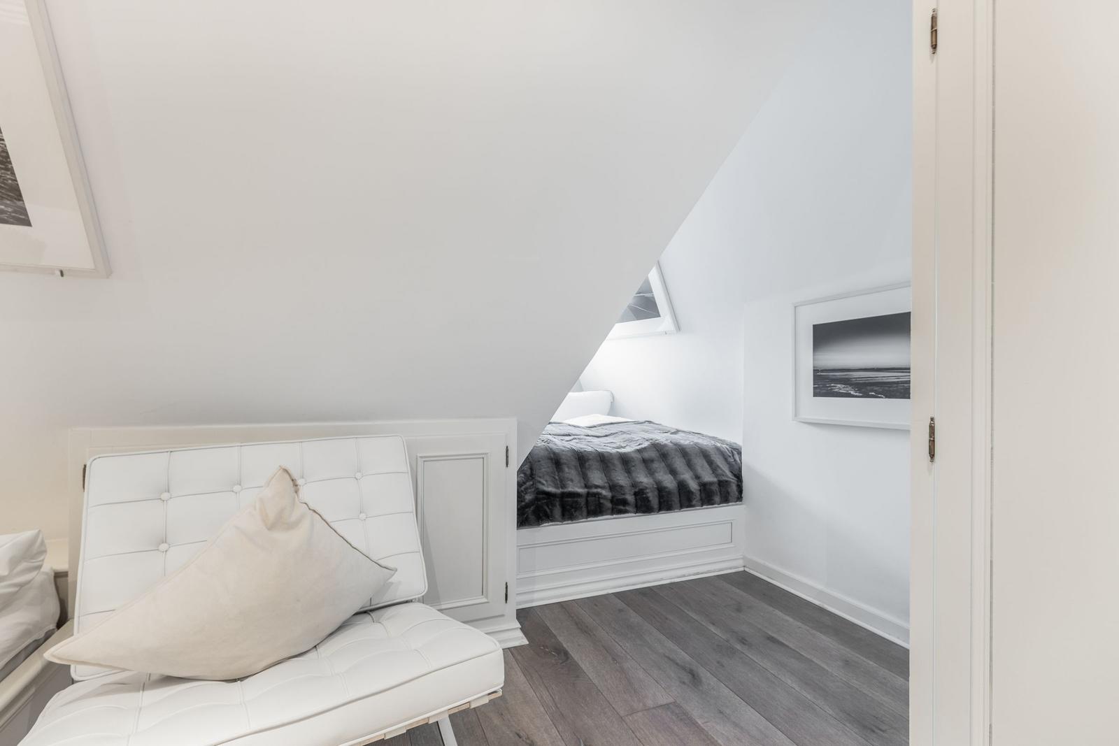 Bedroom with sloped ceiling, white bed, and gray floor