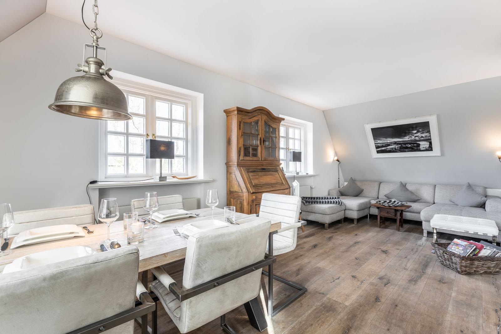 Dining area with table and chairs, living area with sofa and hardwood floor.