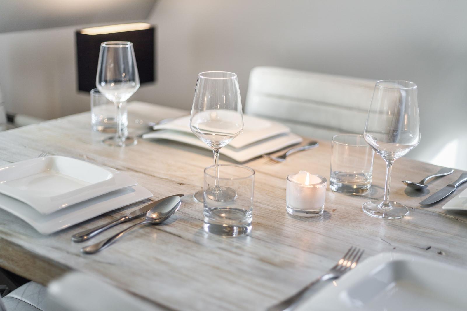Table set with dishes, glasses, and candle for guests
