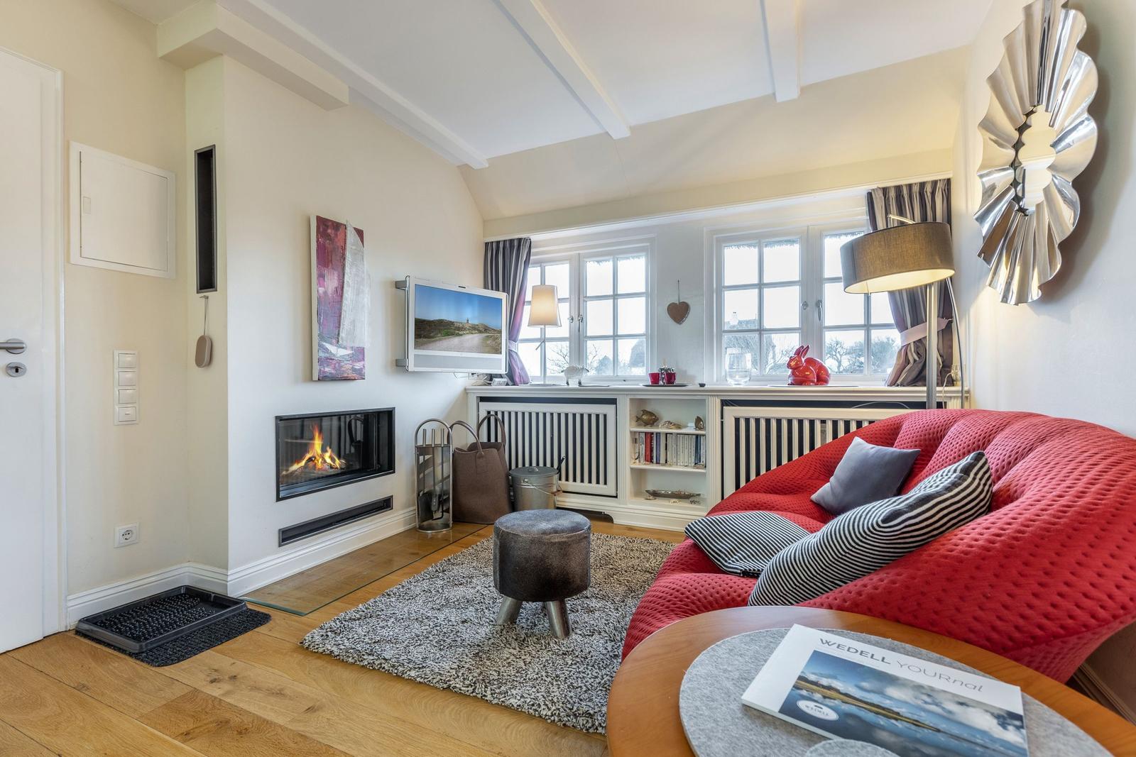 Wohnzimmer mit Kamin, rotem Sofa und Fenster mit Blick.