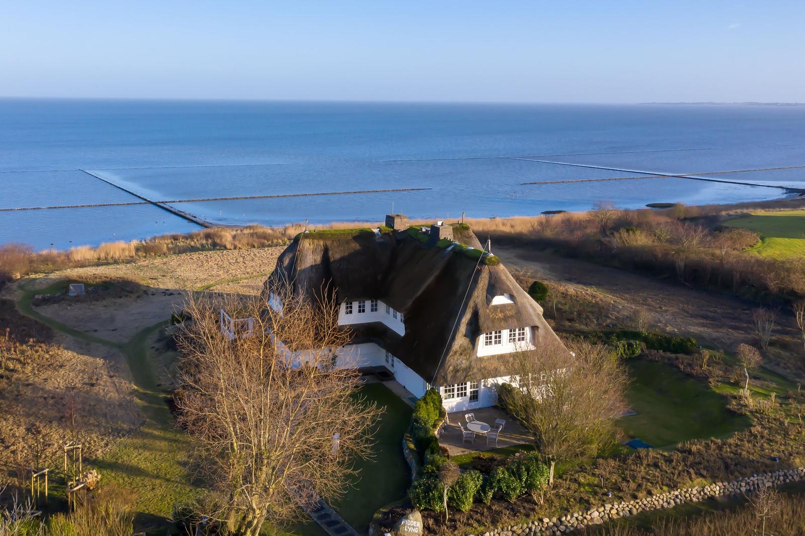 Dorfhaus mit Dach aus Gras, Blick auf Meer und Strand