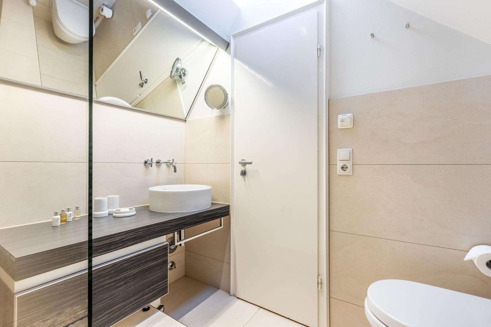 Badezimmer mit Waschbecken, Spiegel und Toilette