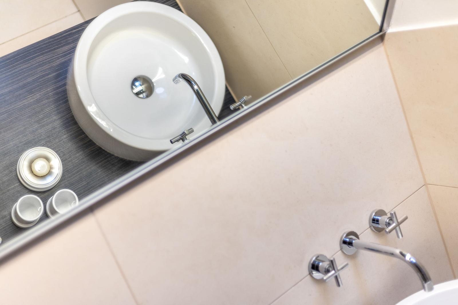 Waschbecken mit Spiegel und Duschbrause im Badezimmer