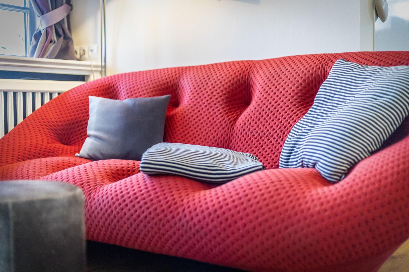 Ein roter Sofa mit Kissen und einem Beistelltisch.