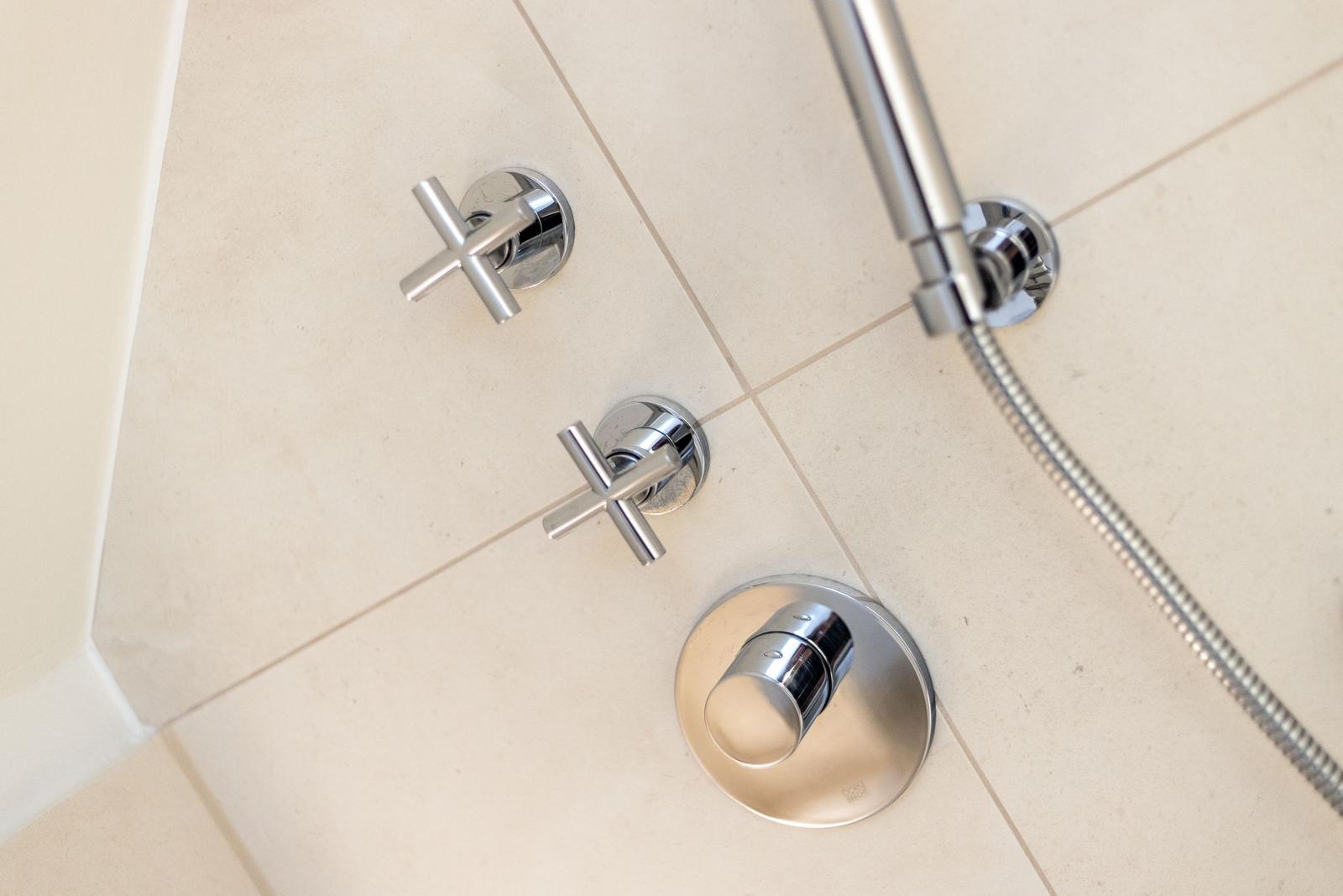 Duschkopf und Wasserhähne an Wand mit Chromfinish