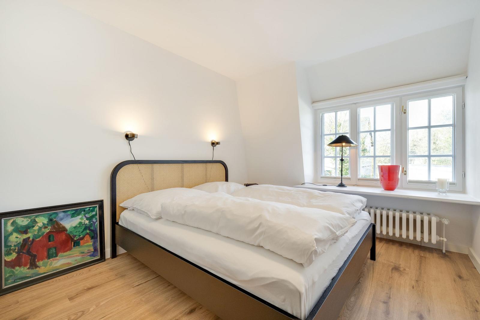 Bedroom with double bed, window, and wooden floor.