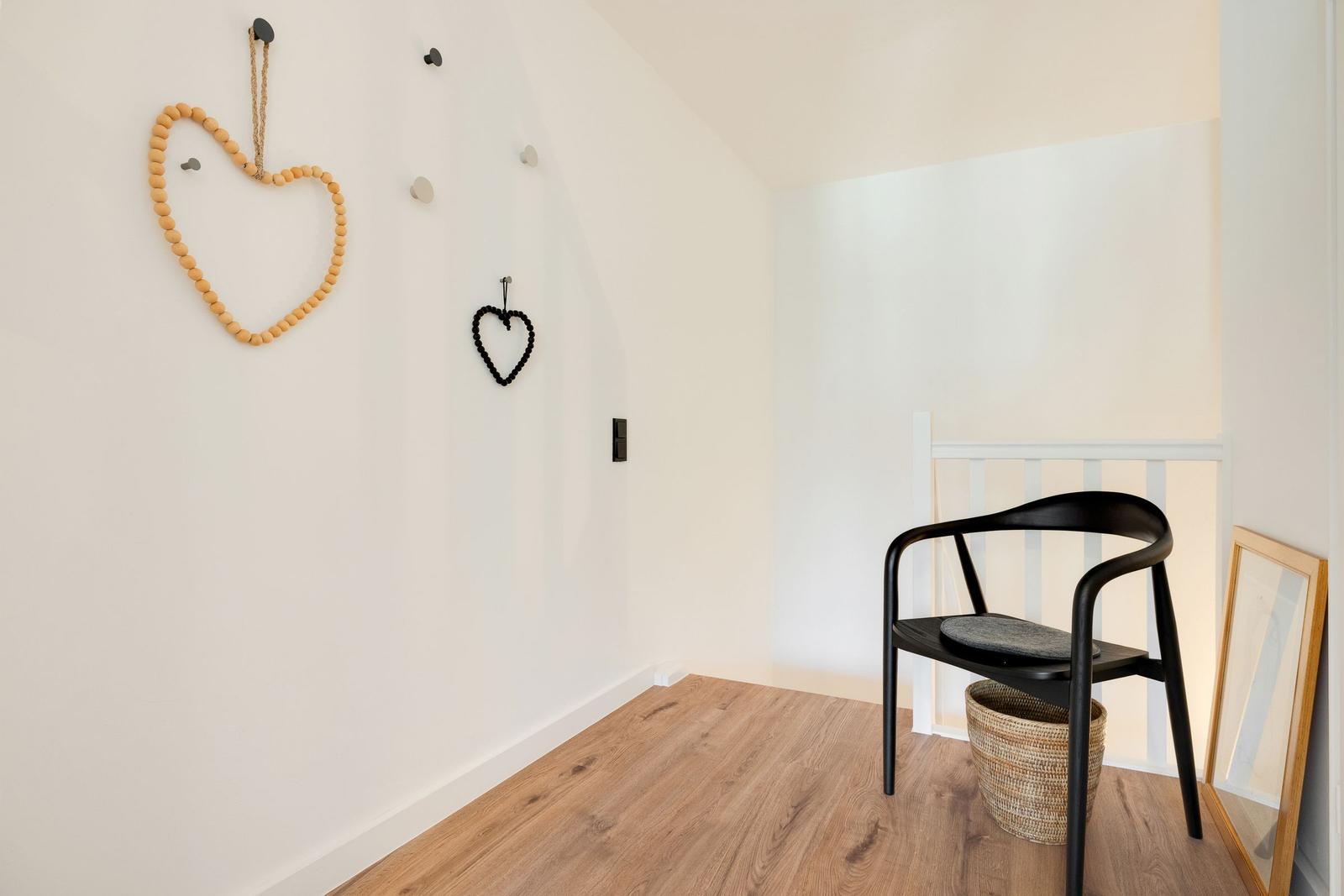 Room with wooden floor, black chair, and heart decor on the wall.