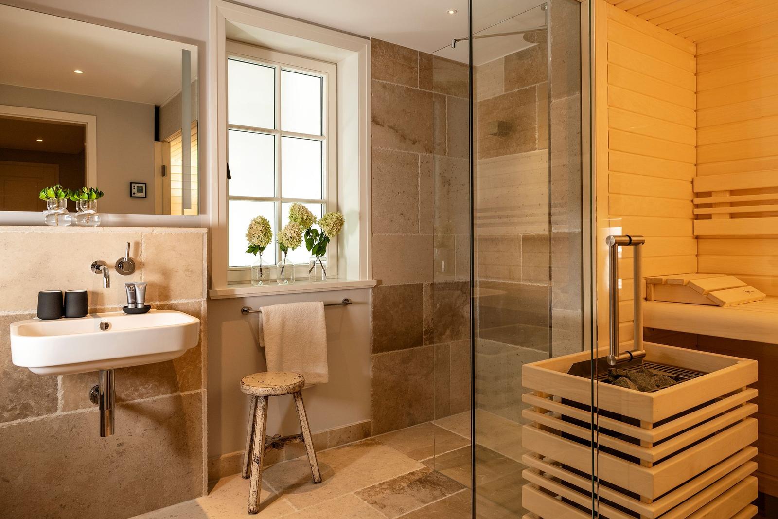Badezimmer mit Dusche, Sauna und Waschbecken mit Spiegel.