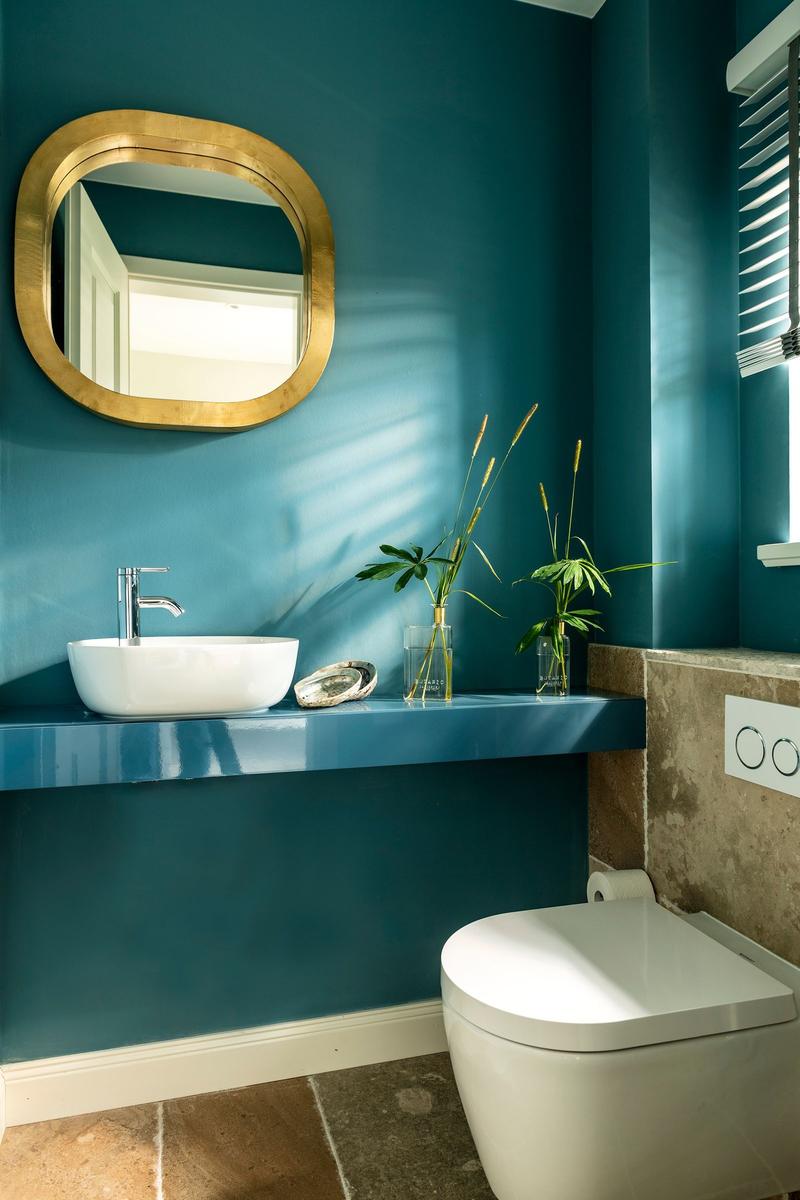 Badezimmer mit blauen Wänden, Waschbecken und Toilette.