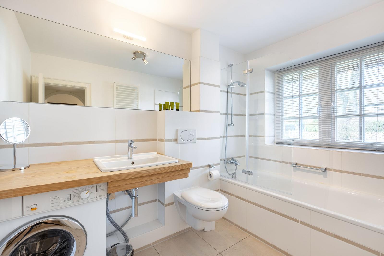 Badezimmer mit Dusche, Waschmaschine und Spiegel
