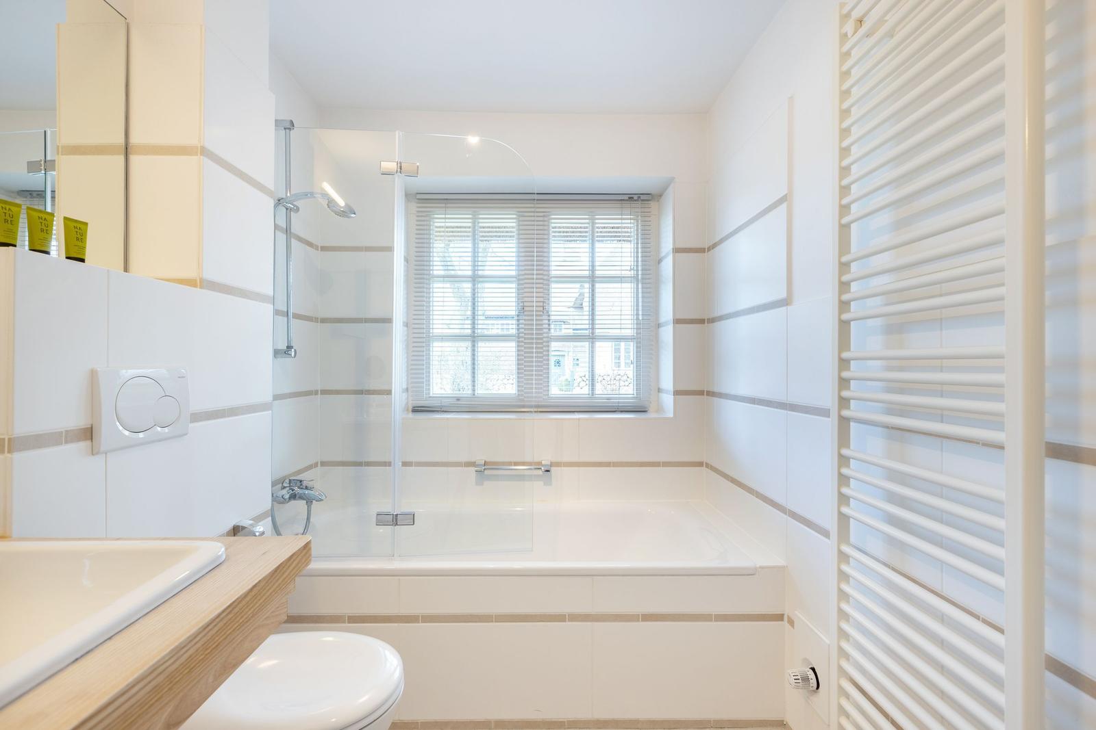 Badezimmer mit Badewanne, Dusche, Toilette und Fenster