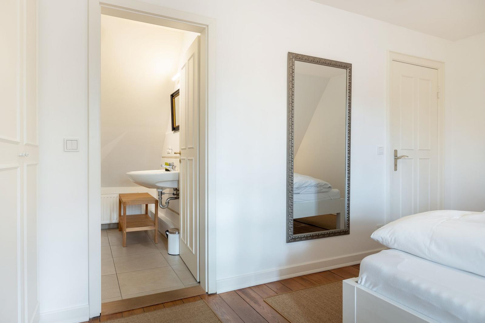Schlafzimmer mit Spiegel und angrenzender Badewanne