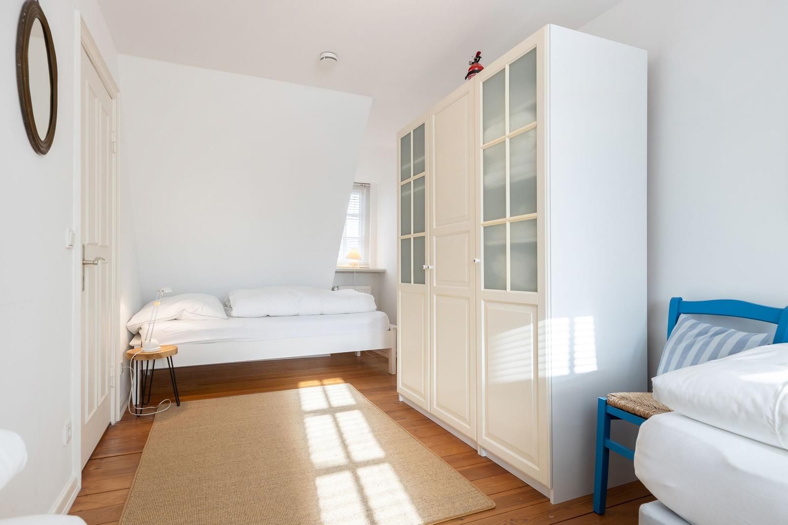 Zimmer mit zwei Betten, Schrank und Holzboden