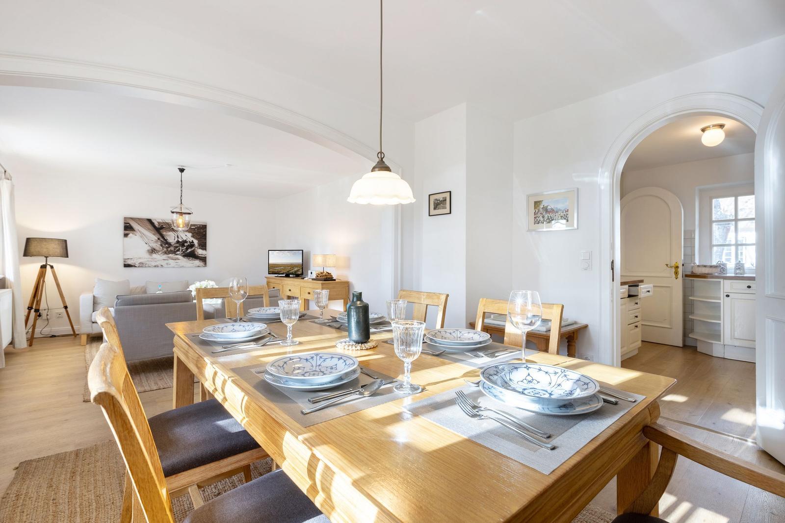 Esszimmer mit Holztisch, Stühlen und gedecktem Tisch. Durchgang zur Küche und Wohnfläche.
